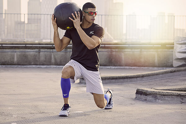 Mann mit Gymnastikball und Reebok Sportbrille